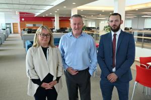 Finance Minister standing with Pat Austin and Jamie Miller from The National Energy Action Charity, smiling to camera